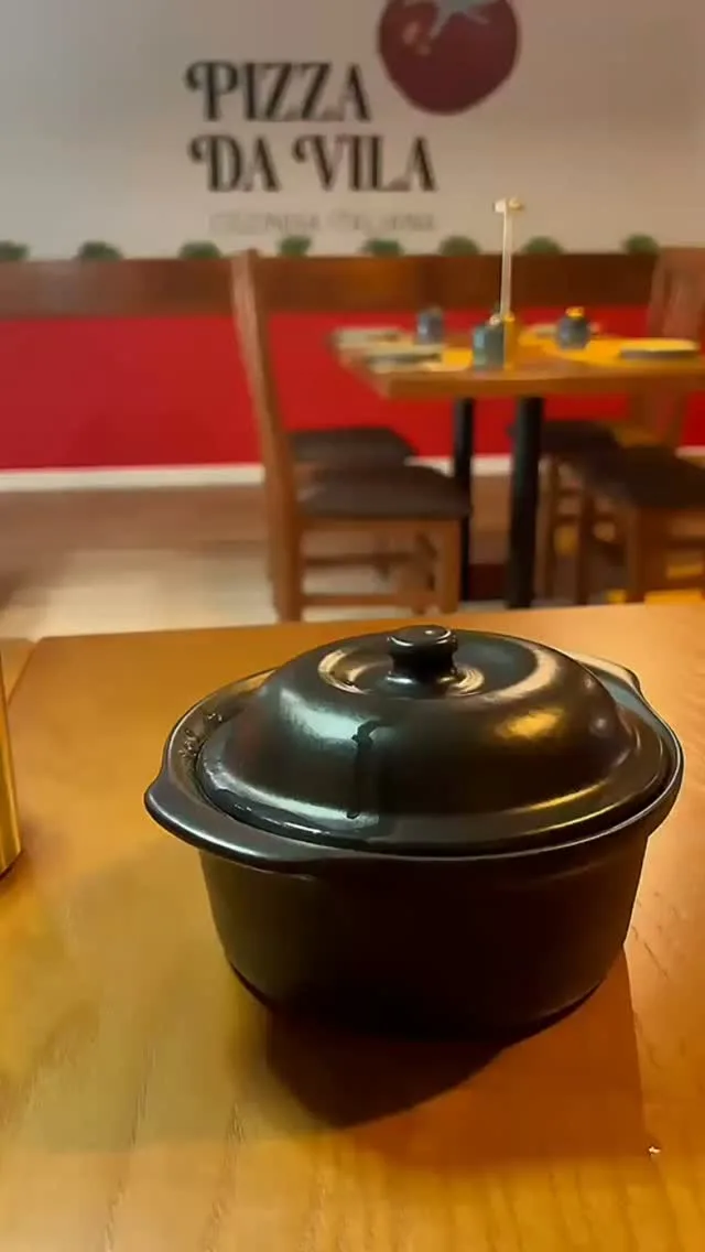 Mesa posta na sala, com uma panela de barro preta
