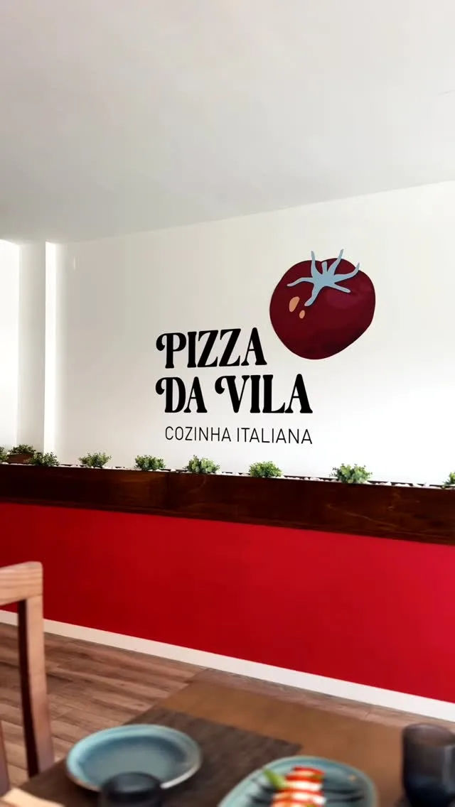 A sala da Pizza da Vila, com o logótipo na parede vermelha e branca